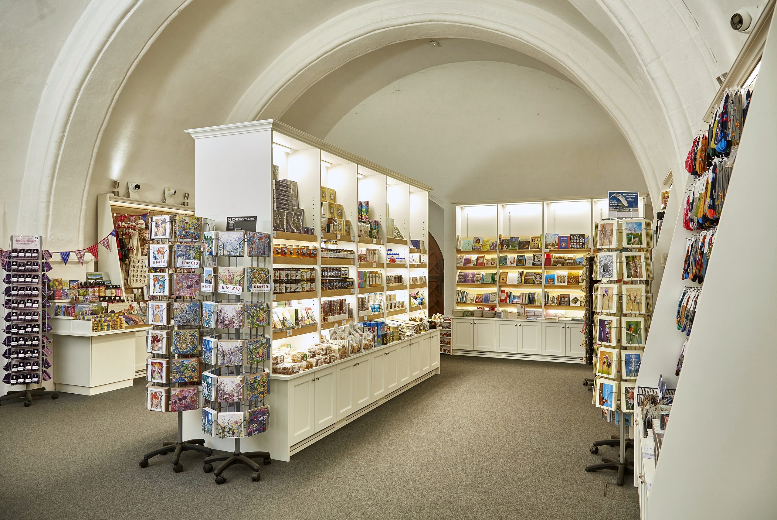 The cathedral shop under its vaulted ceiling, lined with painted cabinetry and lit display shelving