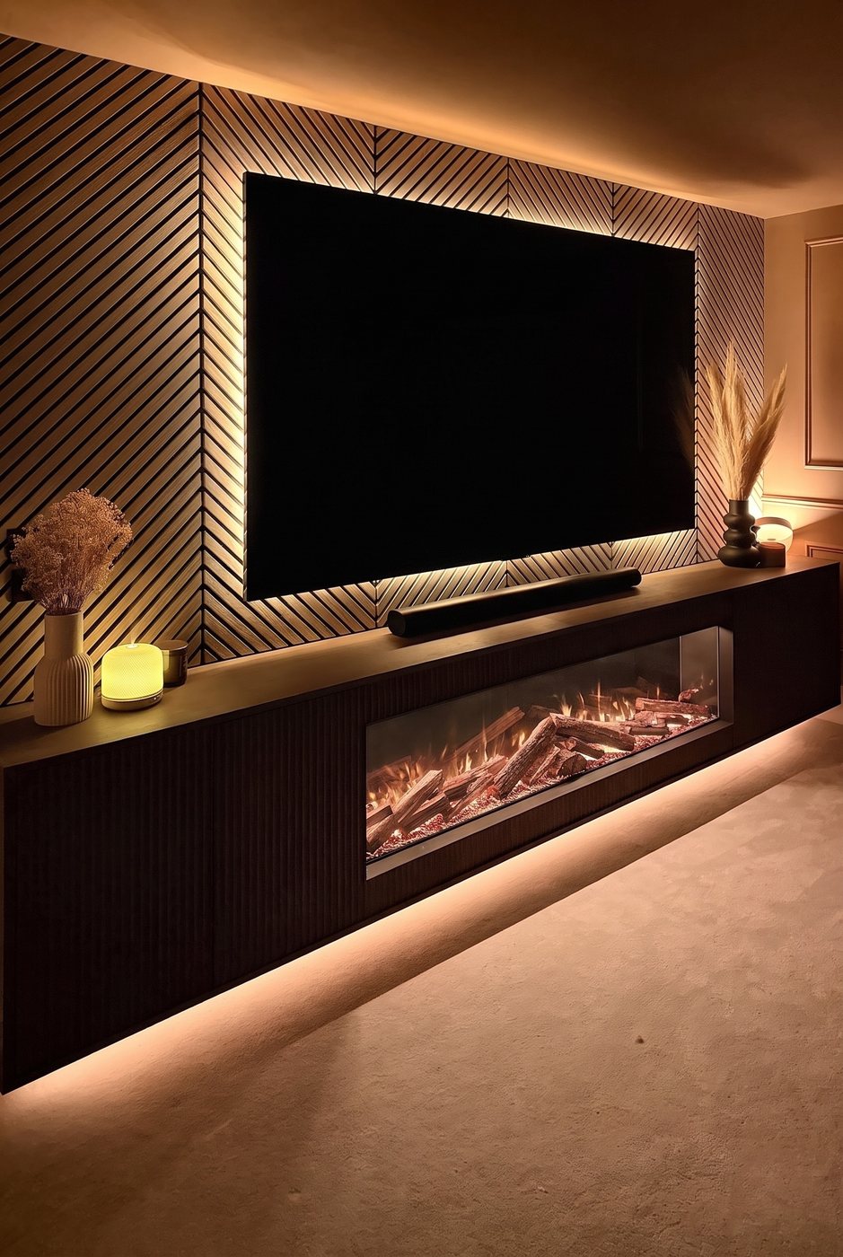Dark fluted media wall with an inset fire and warm backlighting