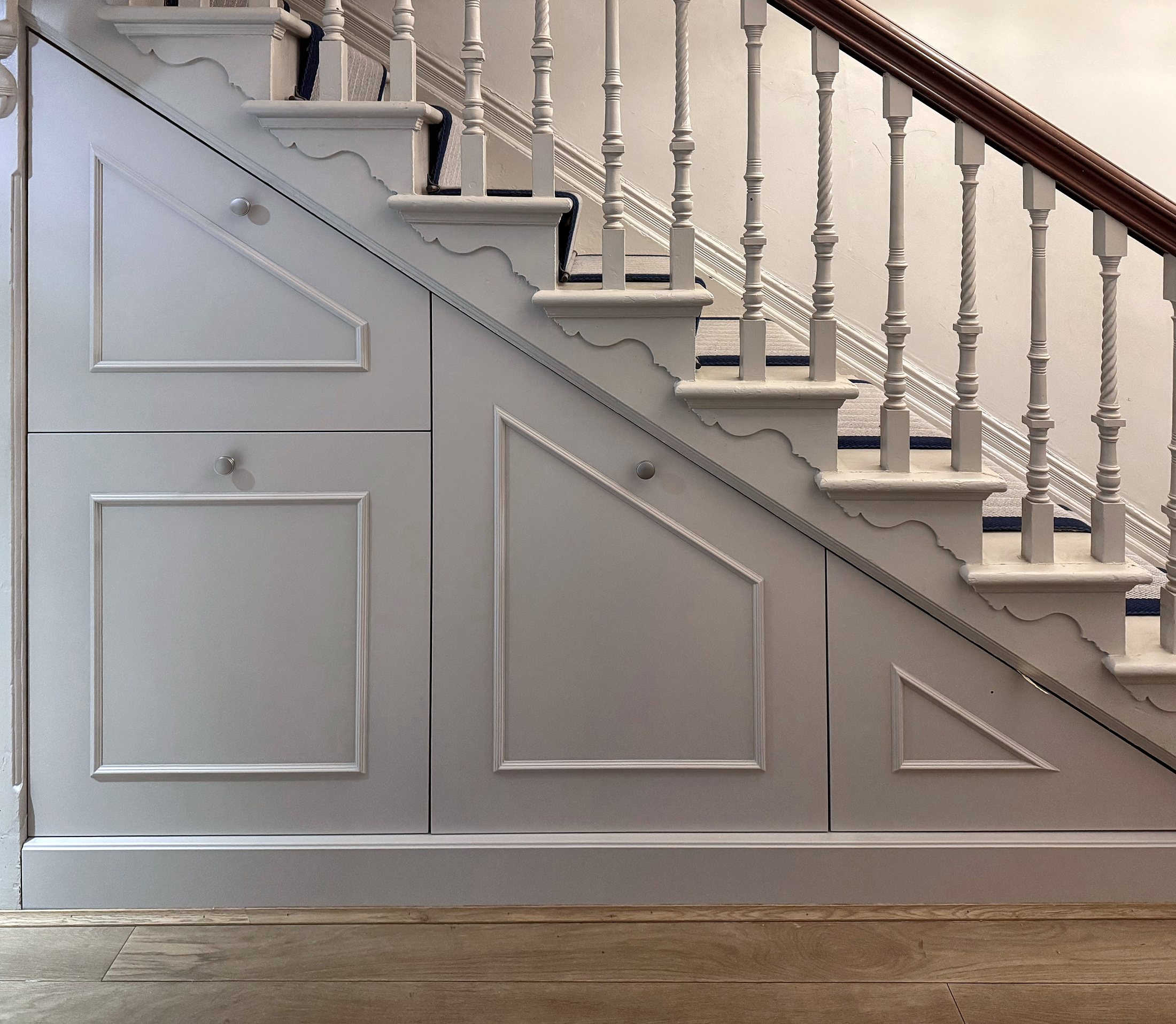 Painted panelled storage built in beneath a period staircase
