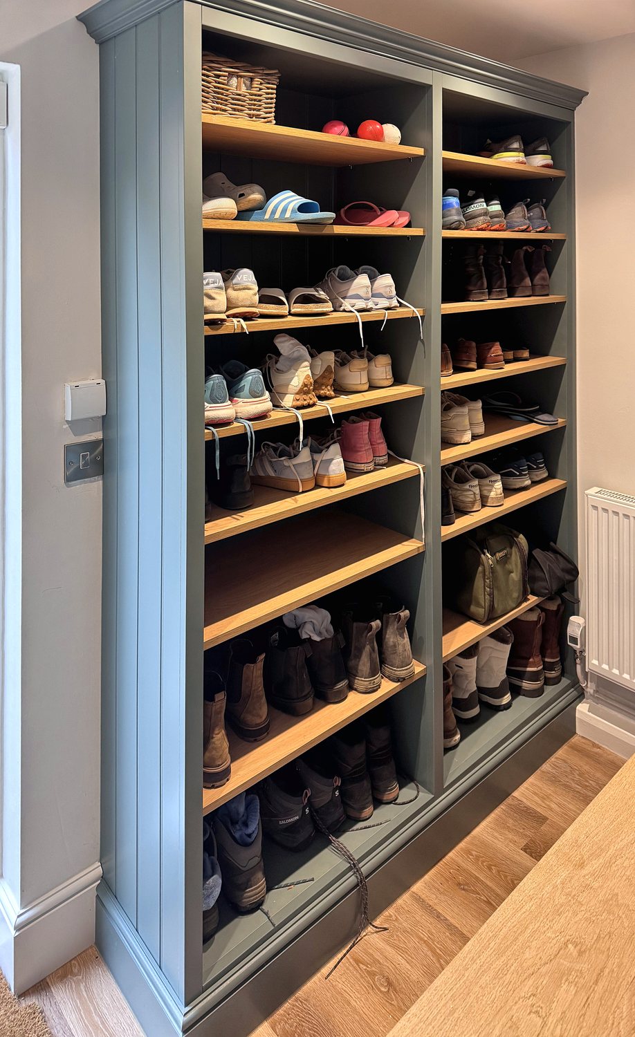 Floor-to-ceiling shoe shelving painted green with oak shelves