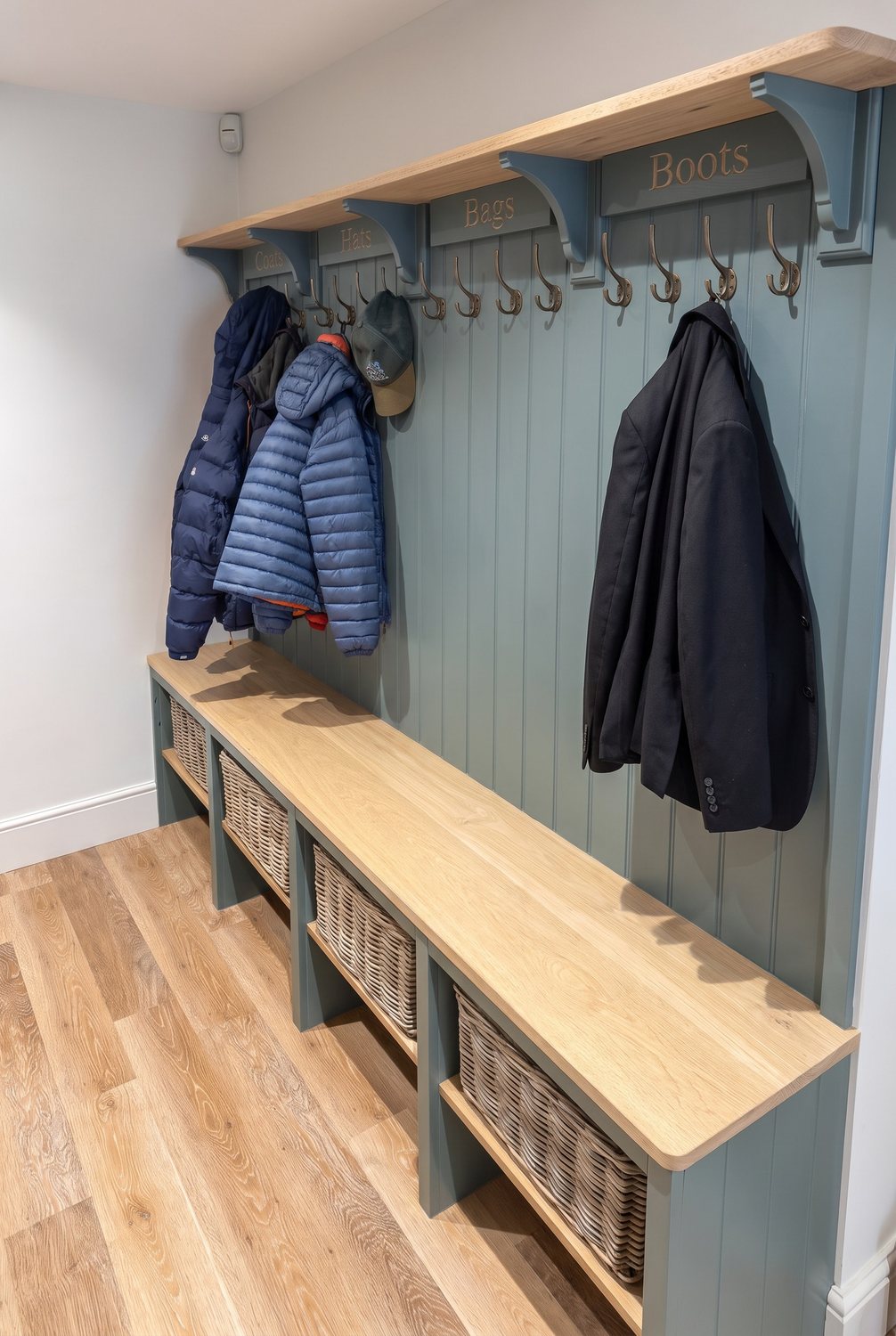 Boot room bench with an oak top shelf, carved plaques reading Coats, Hats, Bags and Boots, coat hooks and woven baskets